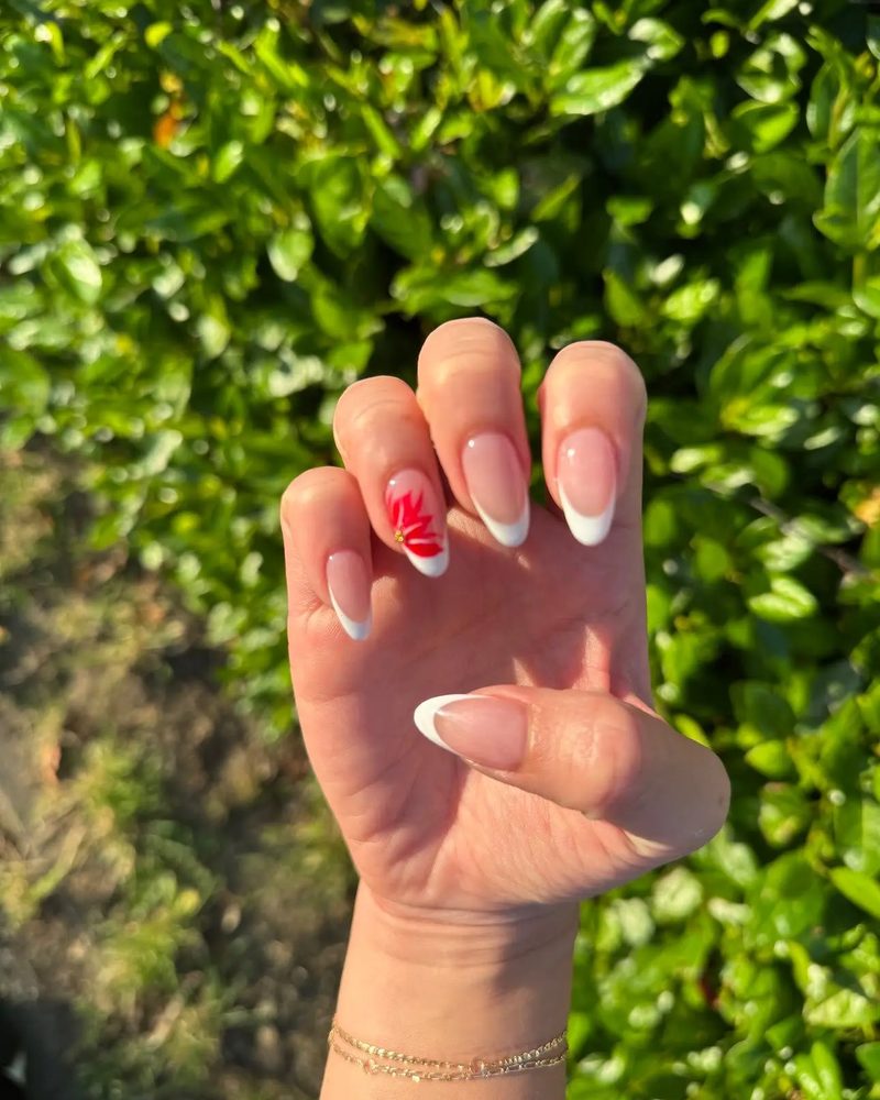 Short almond nails with a white French tip and a small red heart on the ring finger