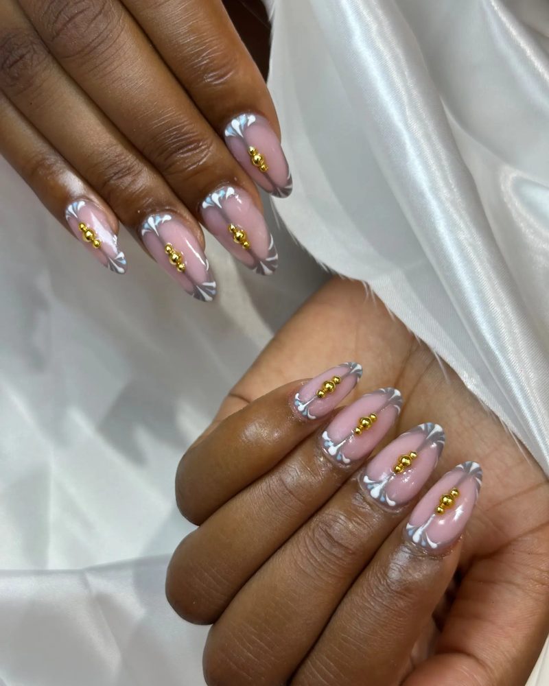 Clear tipped nails with gold leaf flecks and gem accents